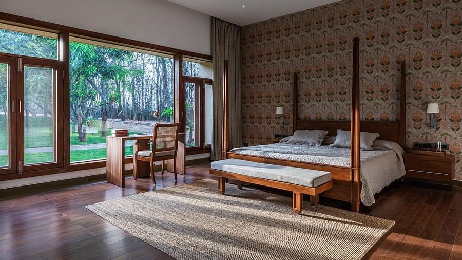 A bedroom with a four-poster bed, large windows, and a brick wall, modern design - Shreyas Retreat