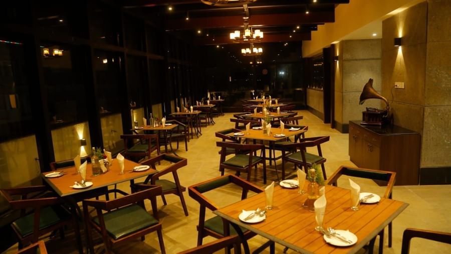 Spacious dining area with tables and chairs set for guests under warm lighting at The Hamuse Hotel, Kodaikanal.