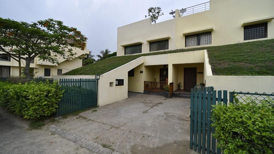 A modern house with a green sloped roof is seen from the outside, featuring a driveway and surrounding greenery | Aqua Bungalow | Vedic Village Spa Resort, Kolkata