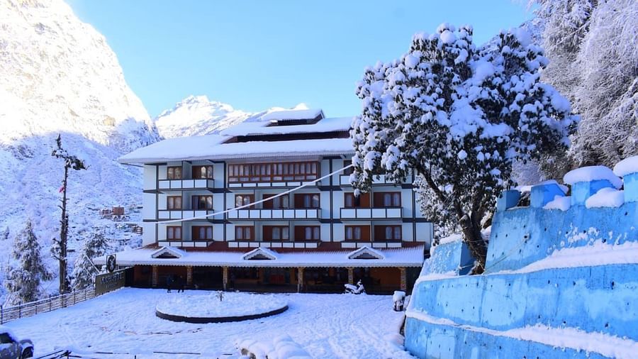 Image of the hotel covered with snow with mountains on either side and few trees   | Yashshree Lachung