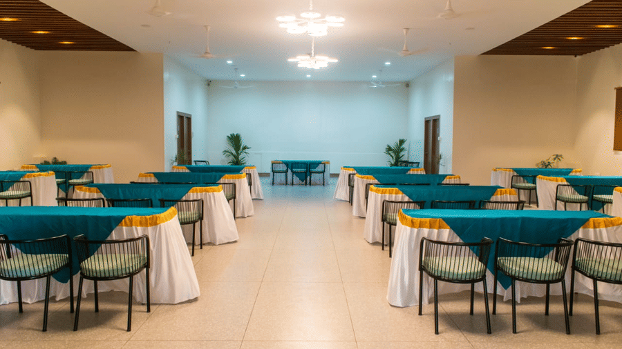 A banquet hall set up for an event with tables and turquoise table cloths - Lords Eco Inn Belagavi