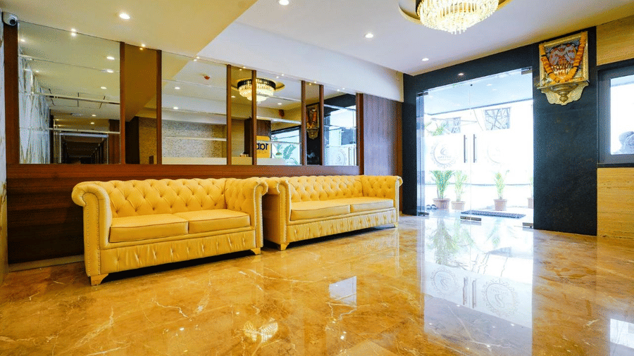 Modern designed spacious lobby with chandeliers, mirrored walls and yellow sofas at Shyanu Lords Eco Inn Airoli