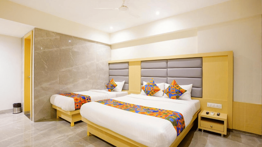 Modern designed sleek room featuring a double bed and a single bed with colourful cushions and runners, grey headboards and a bedside drawer at Shyanu Lords Eco Inn Airoli.