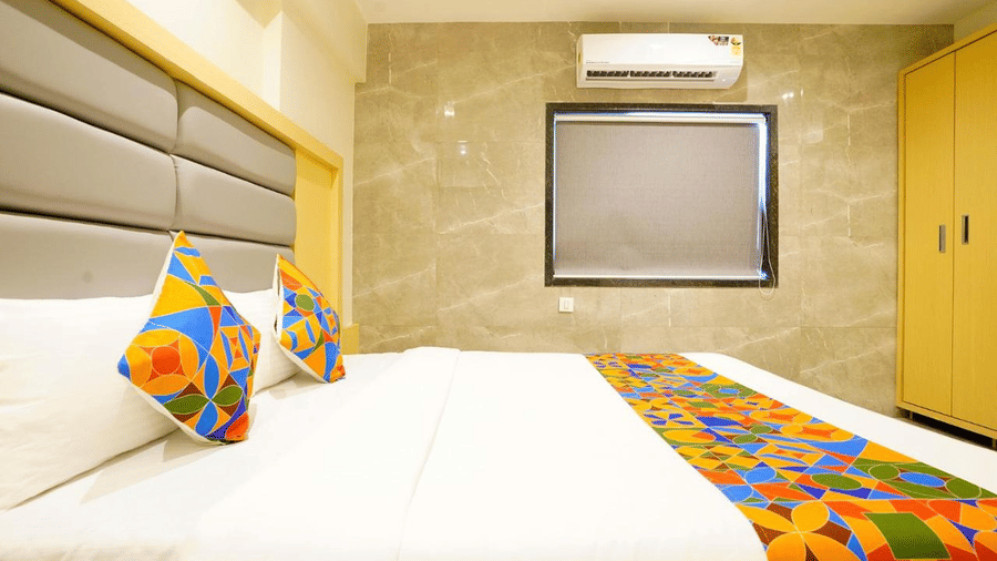 Close-up view of a well furnished room with twin size bed, colourful runner and pillows and grey headboards, a wardrobe and a projector scree at Shyanu Lords Eco Inn Airoli.
