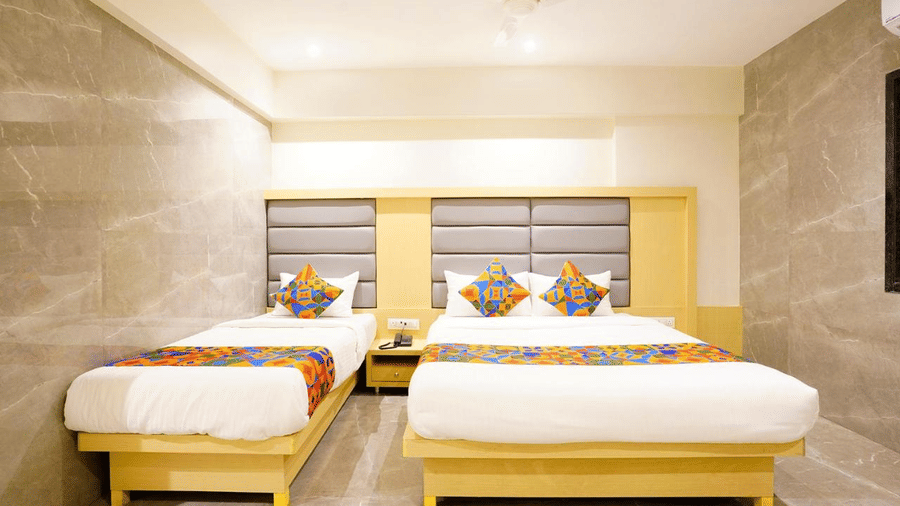 Modern designed room with a twin size bed and a single bed featuring colourful cushions and runners,bedside drawers and grey headboards at Shyanu Lords Eco Inn Airoli.