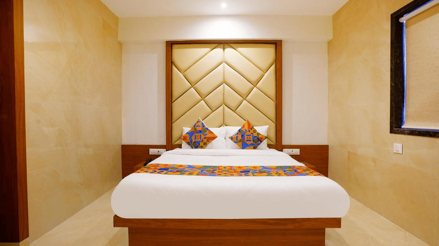 An elegant room with a twin size bed, colourful cushions, patterned headboard and neutral decor at Shyanu Lords Eco Inn Airoli.