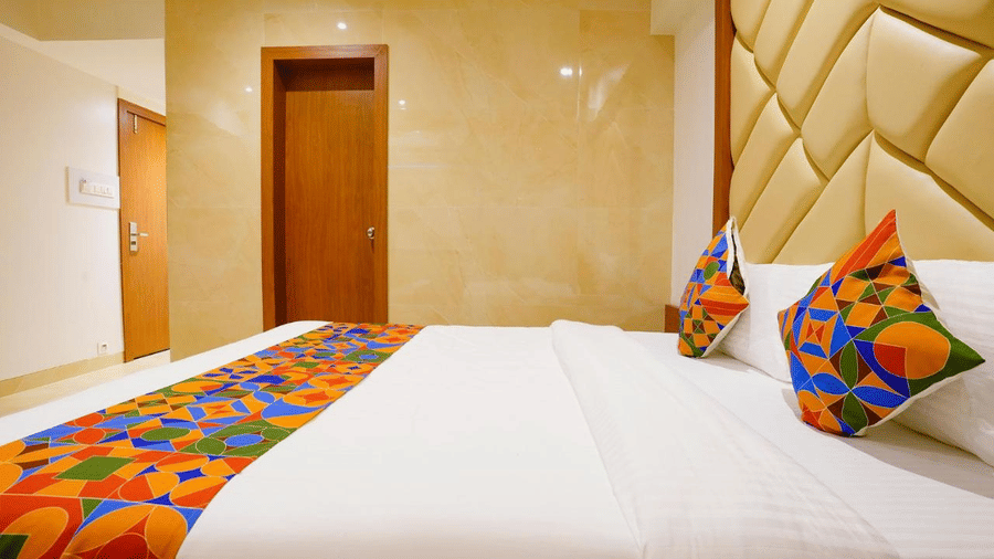 A well furnished room with a twin size bed, colourful pillows and a runner, and textured headboard at Shyanu Lords Eco Inn Airoli.