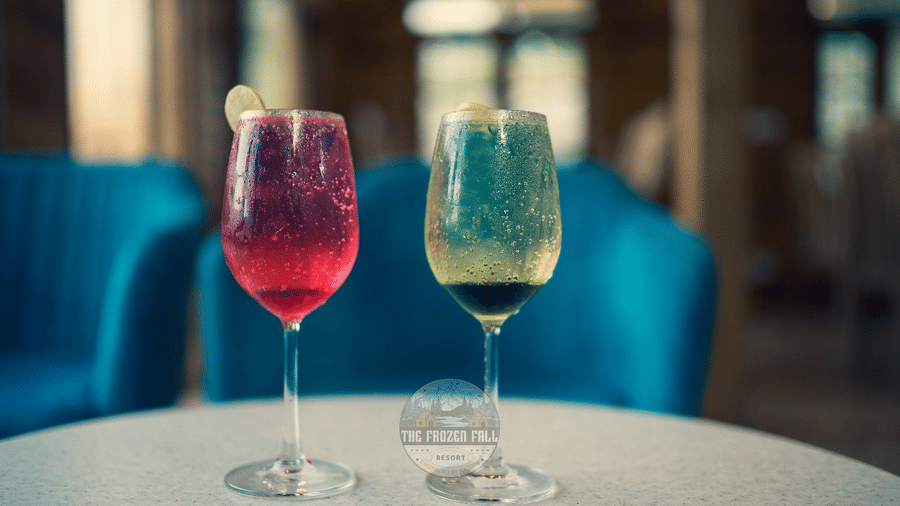 2 stemmed glasses containing beverages placed on a round table in a seating area at Dawat e Drung by FrozenFall Resort, Drung, Tangmarg.