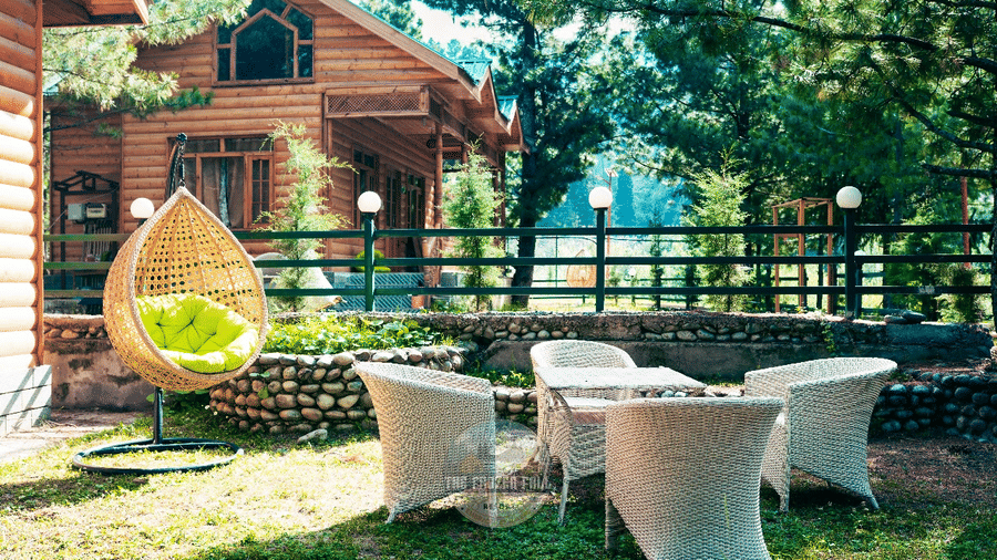 A garden patio space at Dawat e Drung by FrozenFall Resort, Drung, Tangmarg, featuring 4 woven chairs, 1 table and a hanging egg chair structure.