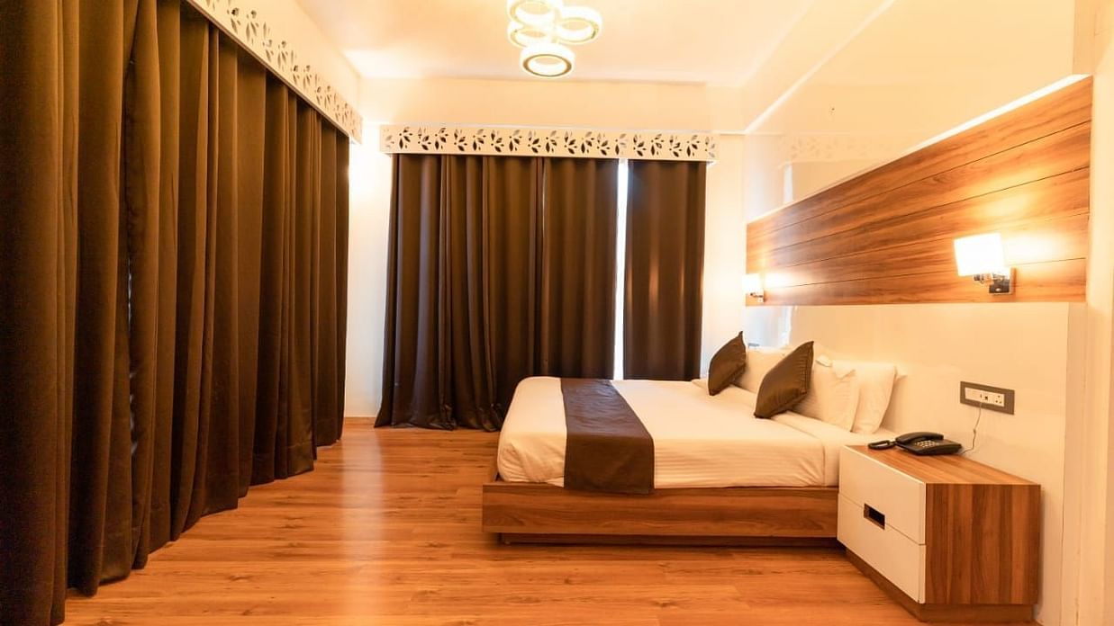 A bedroom with a white bed, a rug, and warm lighting, interior setting - Clarks Exotica Resort, Near Mukhteshwar.