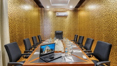 A high-angle view of a professional meeting space with a central laptop, water bottles, and striking gold textured walls at Golden Tulip Kukas, Jaipur.