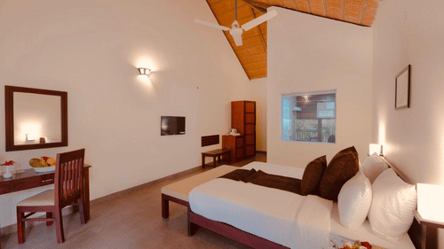 A bedroom with a wooden bed frame features a mirror and a side table, creating a comfortable interior. - Abad Brookside Lakkidi, Wayanad
