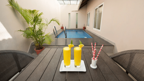 An outdoor table is set with drinks next to a private pool, offering a relaxing poolside experience. - Abad Brookside Lakkidi, Wayanad