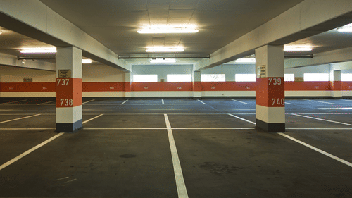 A brightly lit, empty multi-storey car park with clearly marked parking bays.