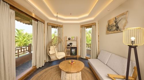 A seating area featuring an attached balcony, an upholstered couch, a lamp, and wall art - Royal Tulip, Chitwan