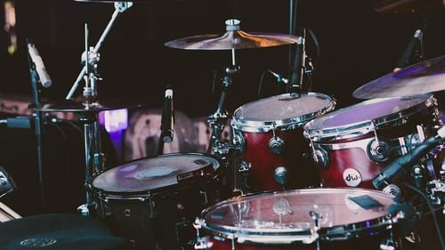 Close-up of a drum set under colourful stage lighting.