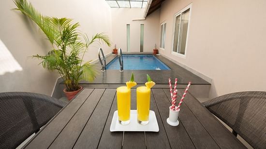 An outdoor table is set with drinks next to a private pool, offering a relaxing poolside experience. - Abad Brookside Lakkidi, Wayanad