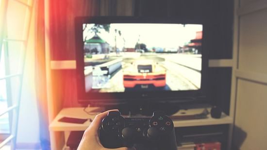 A point-of-view shot of a person holding a controller and playing a car race game on a play station