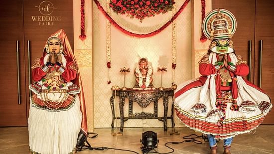 two Kathakali dancers standing on both sides of an idol of lord Ganesha and doing namaste at Uday Palace Convention Centre