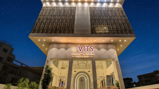 Exterior view of the VITS Select Nashik Hotels & Resorts building with signage and landscaped surroundings as seen during the night.