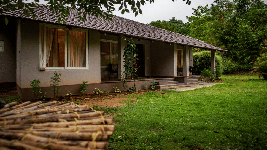 A single-storey house with a tiled roof and a small veranda, set amid a well-maintained lawn. - Abad Brookside Lakkidi, Wayanad