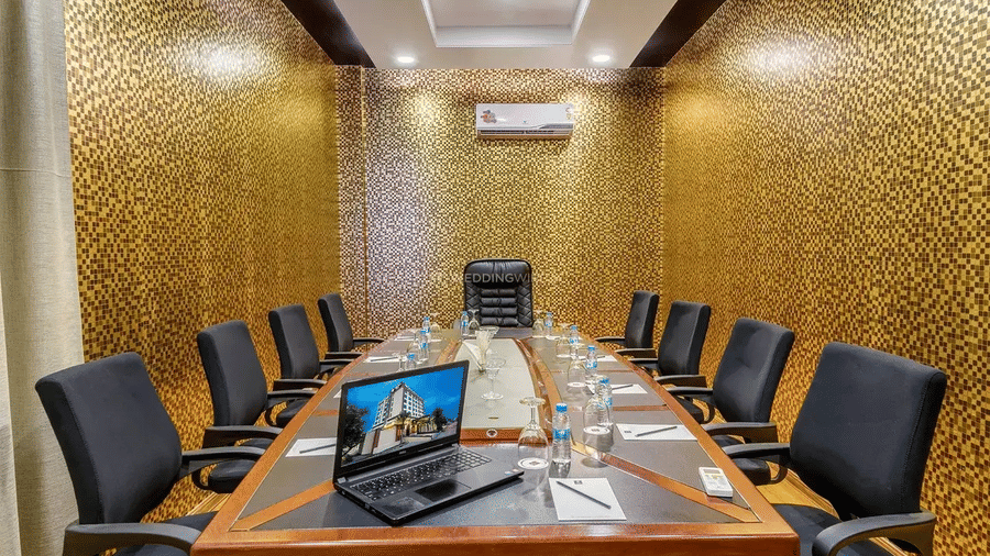 A high-angle view of a professional meeting space with a central laptop, water bottles, and striking gold textured walls at Golden Tulip Kukas, Jaipur.