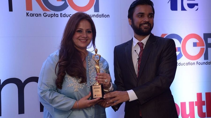 Kiran Bawa receiving an award by a man while posing for a picture - IOSIS Spa & Wellness