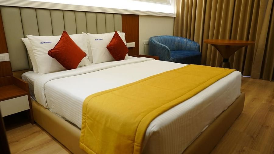 Bright and spacious queen room with yellow bed runner and seating at Kalyan Residency Hotel, Tirupati.