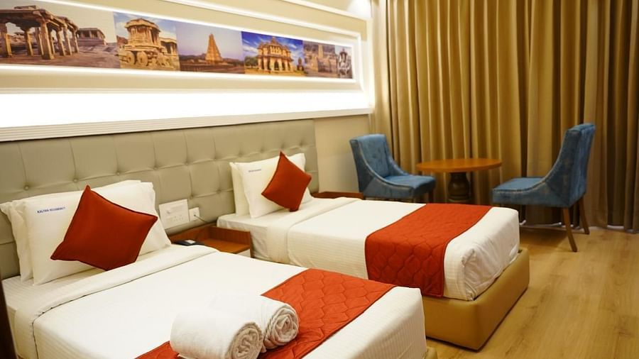 Bright twin room with rolled towels, artwork, and seating at Kalyan Residency Hotel, Tirupati – perfect for a relaxed stay.