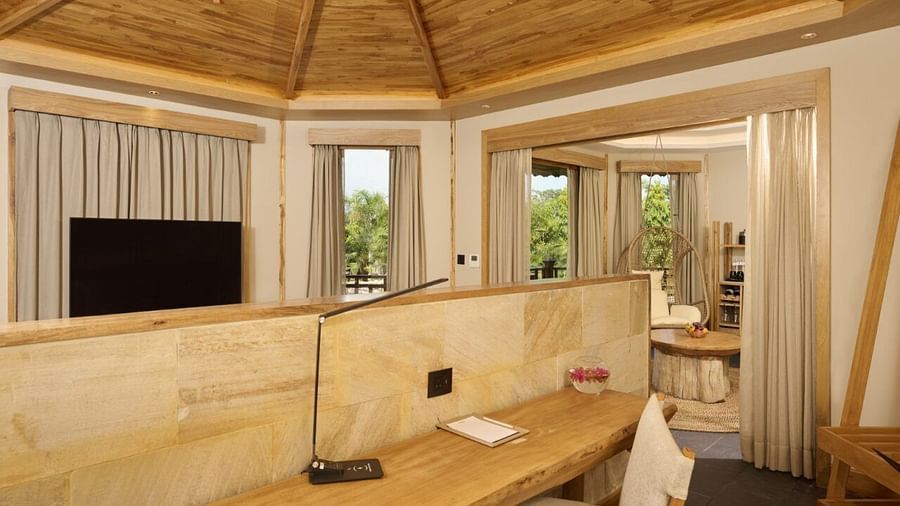 The work desk at our villa in Chitwan featuring a table, a chair, a night lamp, and a window with lush green views - Royal Tulip, Chitwan