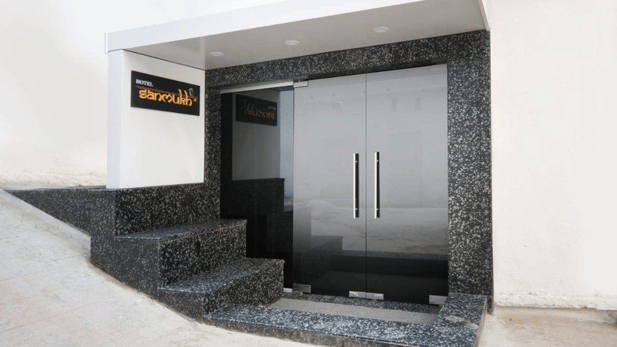 main entrance door of Adamo Sanmukh  with the name template on a wall next to stairs.