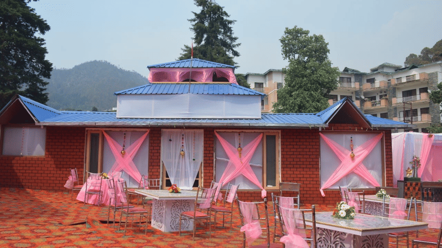 A colorfully decorated setting with seats, chairs and tables, and a background of the trees and hills