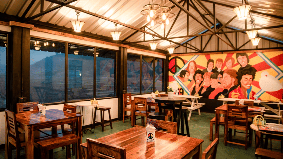 A dining space at Woodstock Farmhouse, Shillong, with chairs, and tables arranged at a well-lit space.