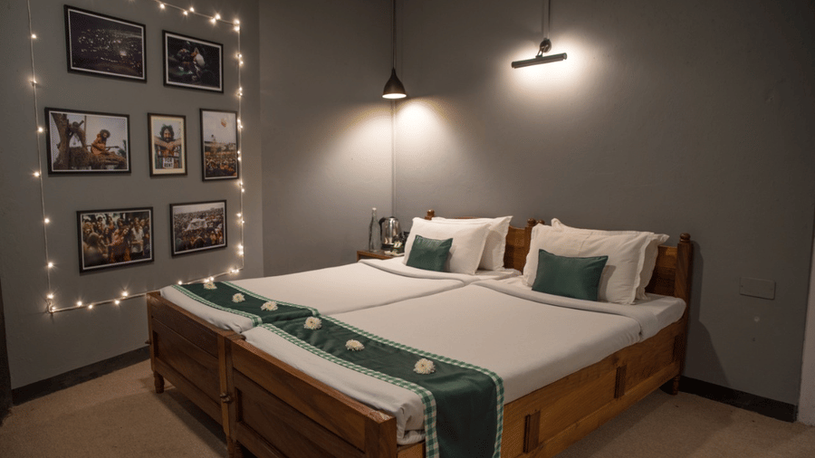 A room at Woodstock Farmhouse, Shillong, featuring a large bed, bedspreads, pillows, and wall art.