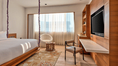 Hotel room in South Goa with wooden interiors, furniture and a white bed that offers in-room massage