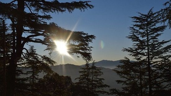 Sunrise over a calm mountain landscape with misty clouds.