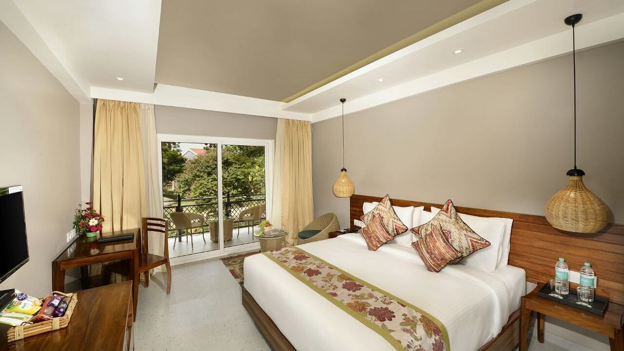 A room at Swosti Chilika Resort with a double bed and a balcony with seating arrangement