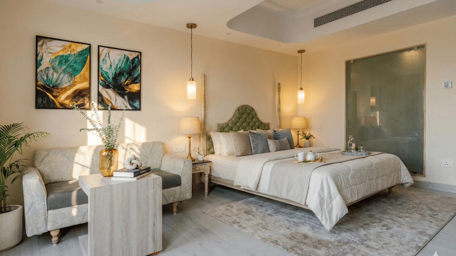 A wide-angle shot of the Superior Room at Essentia Luxury Hotel and Convention, Nagpur, featuring a plush double bed with brightly lit bedside lamps hanging from the ceiling, and a couch in the corner.