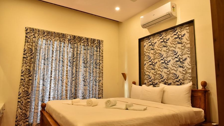 Cosy bedroom with a wooden bed, soft lighting, and patterned curtains, offering a warm and inviting atmosphere.