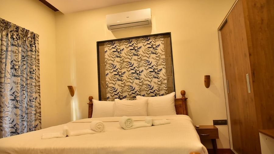 Cosy bedroom with a neatly made king size bed, wooden wardrobe, and soft lighting for a relaxing stay.