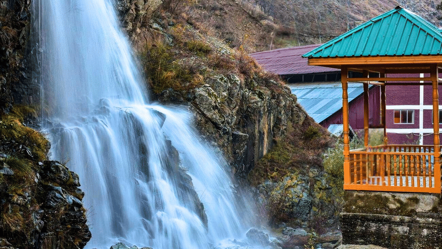 A waterfall cascading over rocky cliffs next to 1 small wooden viewing pavilion with a roof, located near the property.
