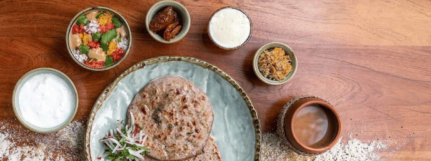 Flat lay of a plated dish with flat breads, dips, radishes, and herbs served at Karma Chalets | Organic Food in Gurgaon