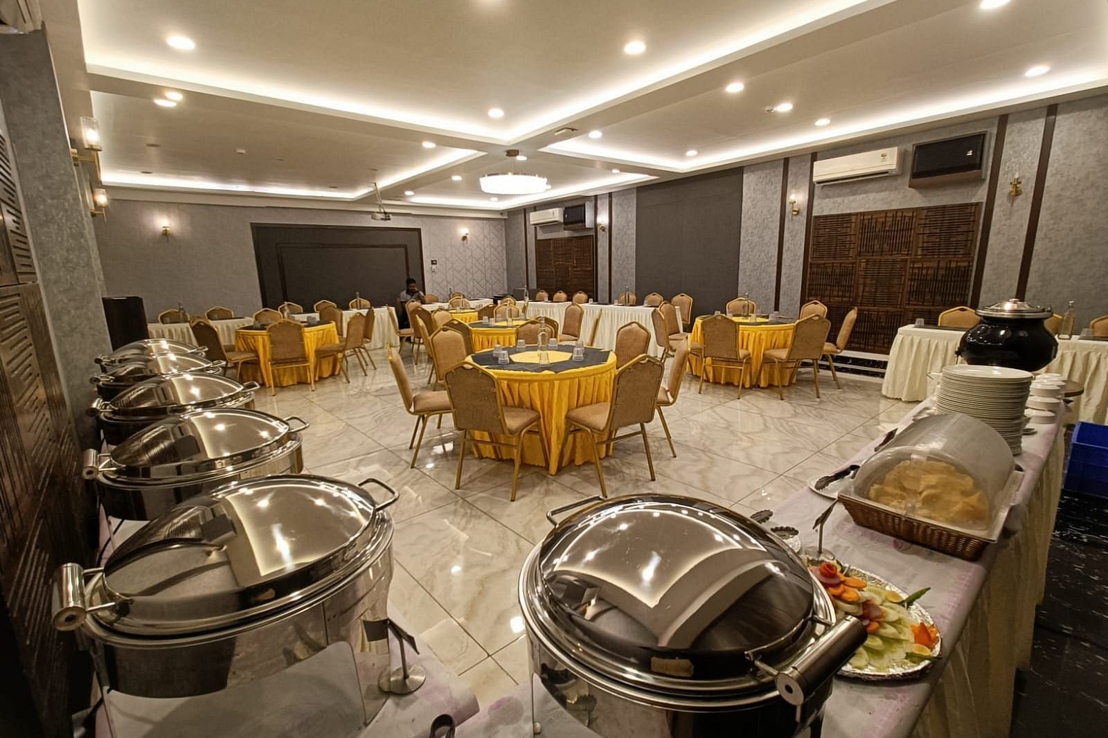 image of event hall with yellow chairs and tables and buffet system placed at the corner at Hotel Eastern Gate, Port Blair