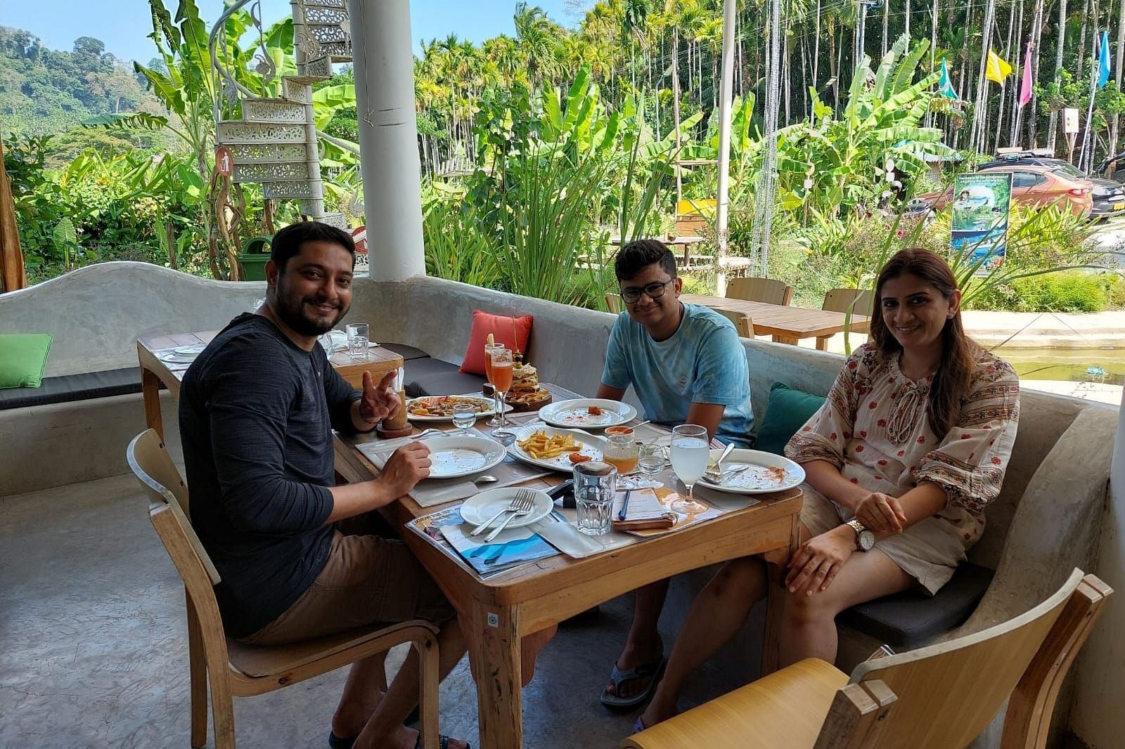 Dining scene - outdoor diner with three tables in view and three people posing for the camera, seemingly happy with the food and ambience.