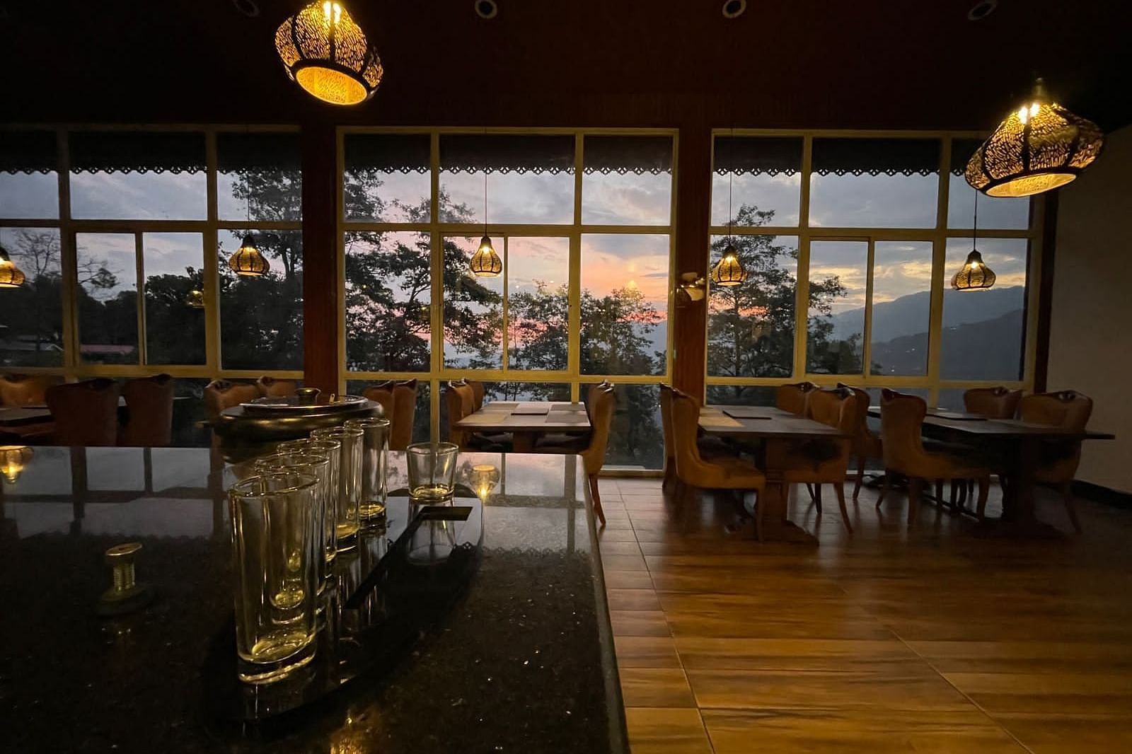 Overview of the Restaurant with seating arrangements and large windows with a view - Sumitel Gangtok