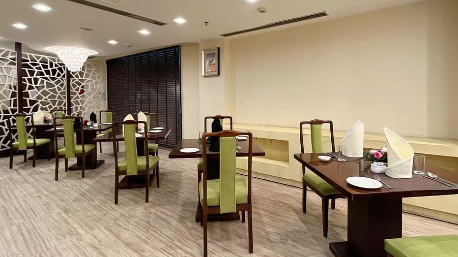 An image of a restaurant at Five Elements Hotels North Avenue, Delhi featuring several sets of chairs and tables and bright ceiling lights