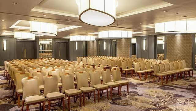 A stylish interior design featuring hanging lights and neatly arranged chairs in the hall at The Residency Towers Puducherry