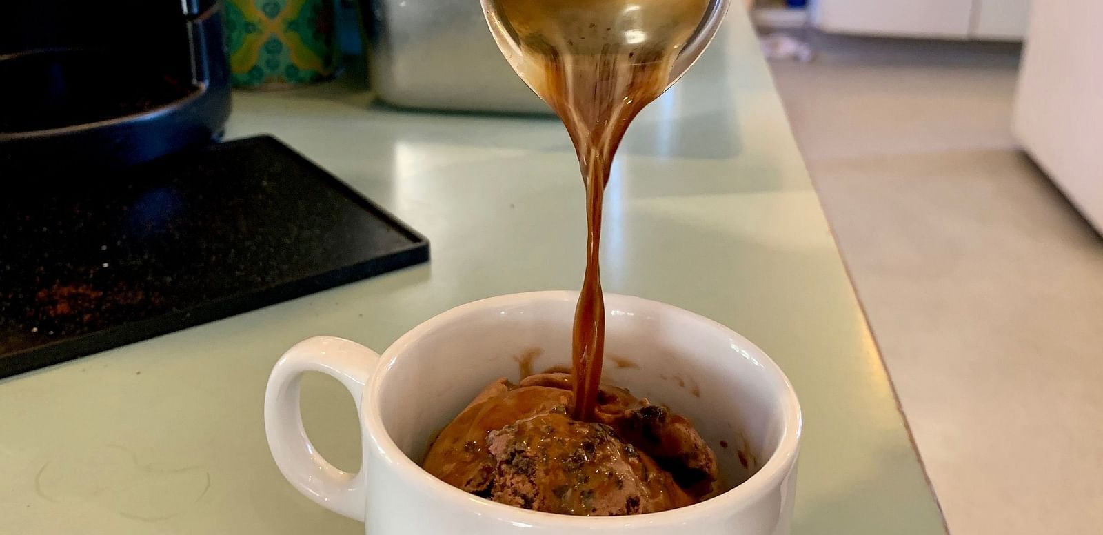 Liquid is poured from a metal pitcher into a mug.