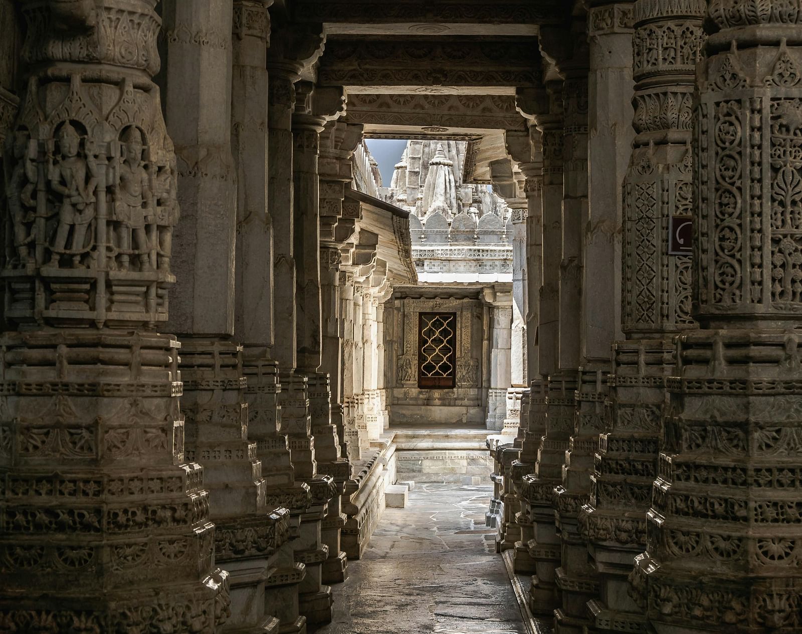 A dimly lit interior of an Indian temple showcasing the intricate architecture on the pillars.