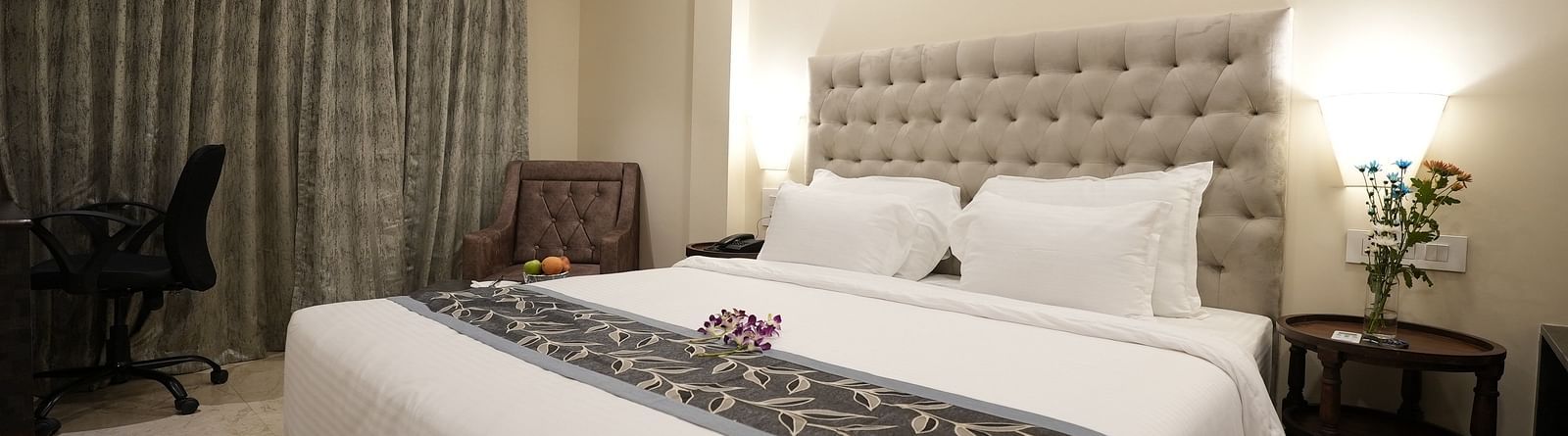 Modern hotel room with a work desk, large bed, and grey curtains at The Verda de Miranda Resort.